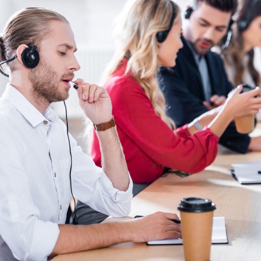 selective-focus-of-call-center-operators-working-at-workplace-with-coffee-to-go-in-office