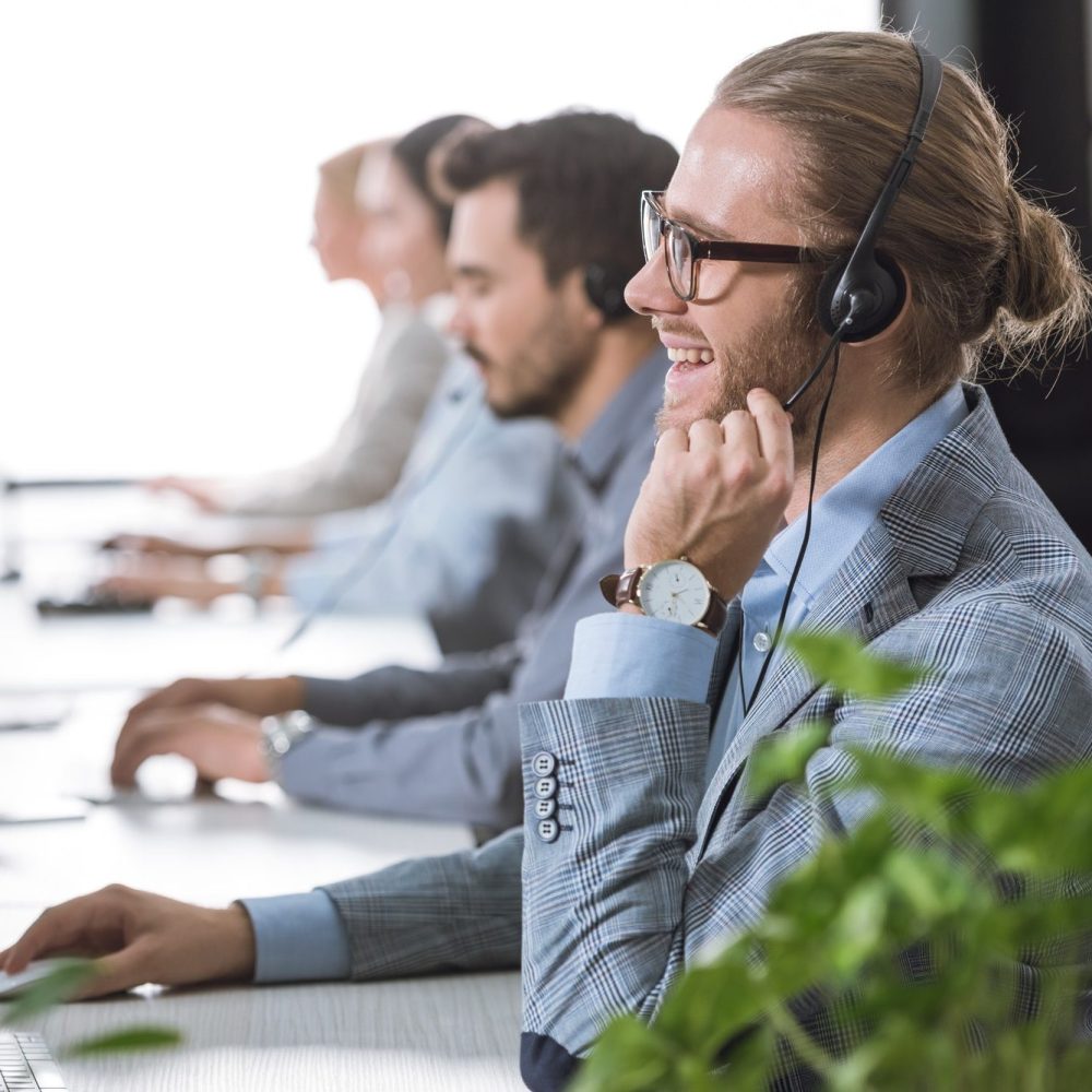 selective-focus-of-cheerful-call-center-operator-in-headset-working-in-office-e1640060053582